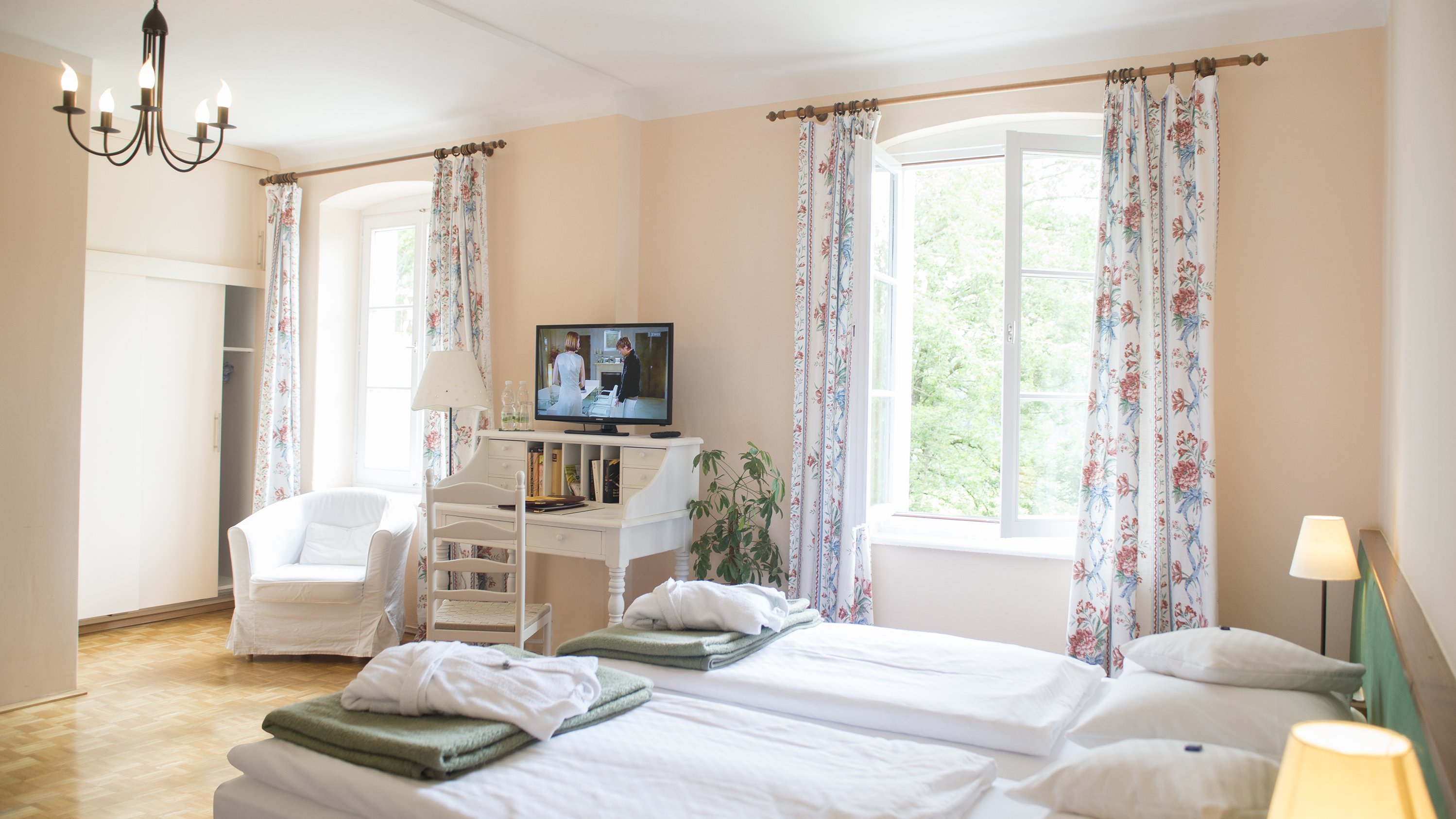 Comfortable hotel room with modern design Hotel room featuring two beds, a television, and a seating area with a chair by large windows