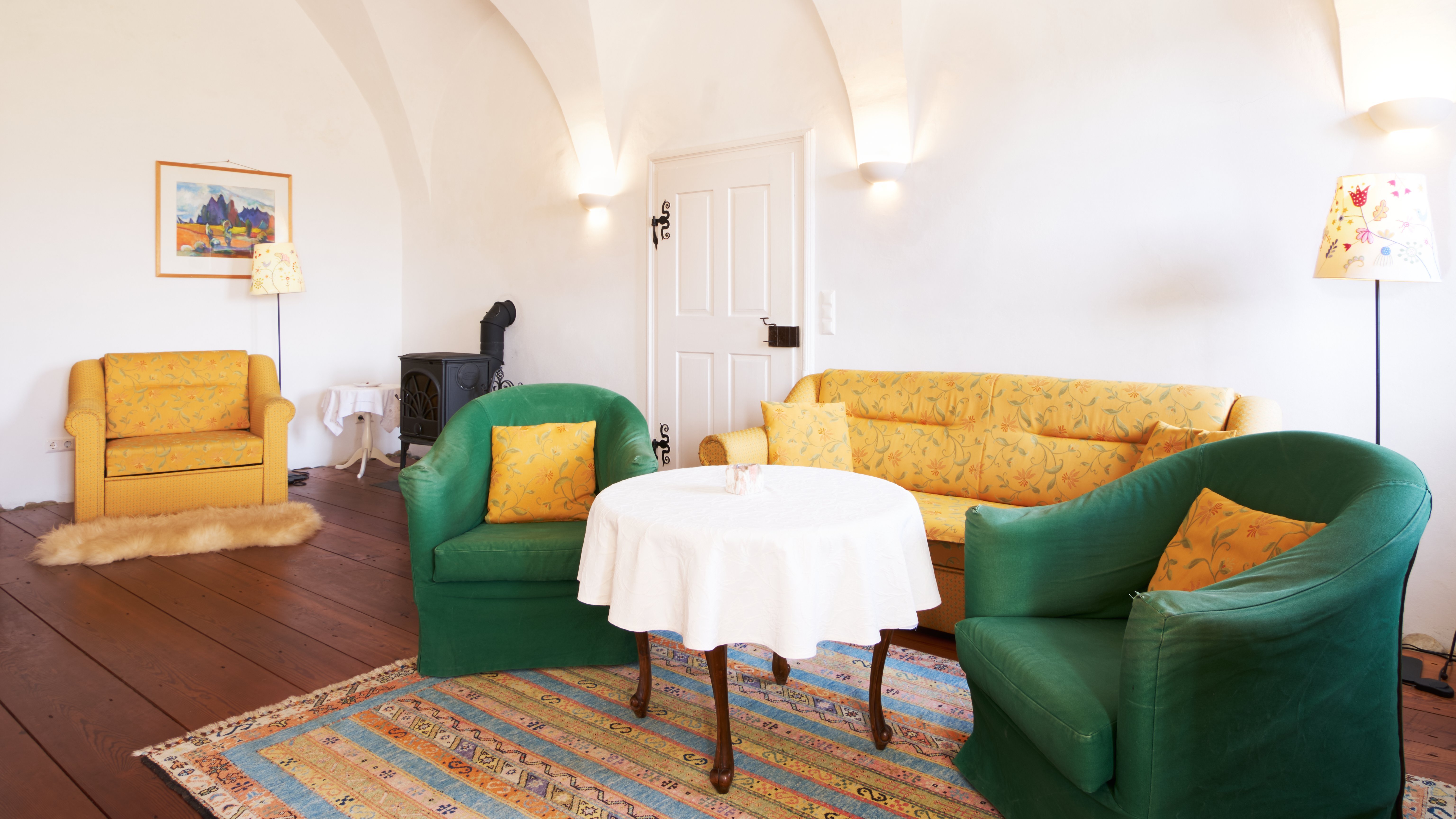 Cozy Living Room Ambiance A living room featuring yellow and green furniture, a round table and decor elements.