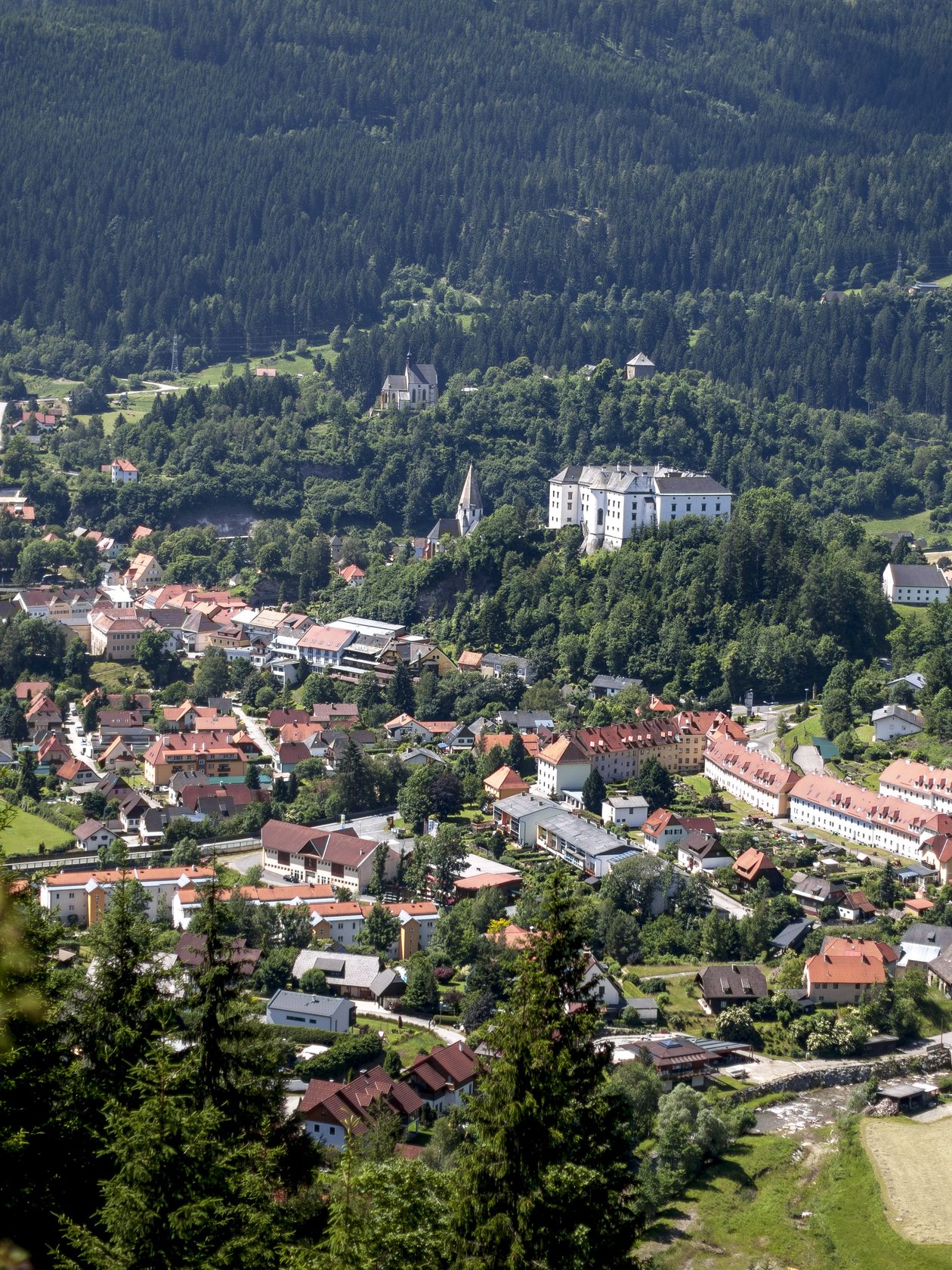 Idyllisches Bergdorf inmitten der Natur Luftaufnahme eines Bergdorfes umgeben von grüner Landschaft und Hügeln mit sichtbaren Gebäuden