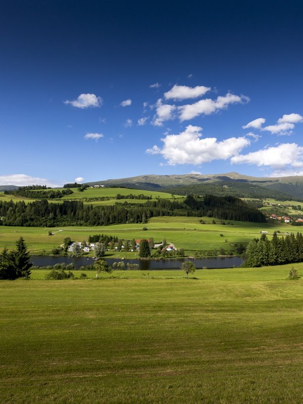 Eindrucksvolle Landschaft im Naturpark Landschaft mit Hügeln, einem klaren See und Bergen unter blauem Himmel mit Wolken