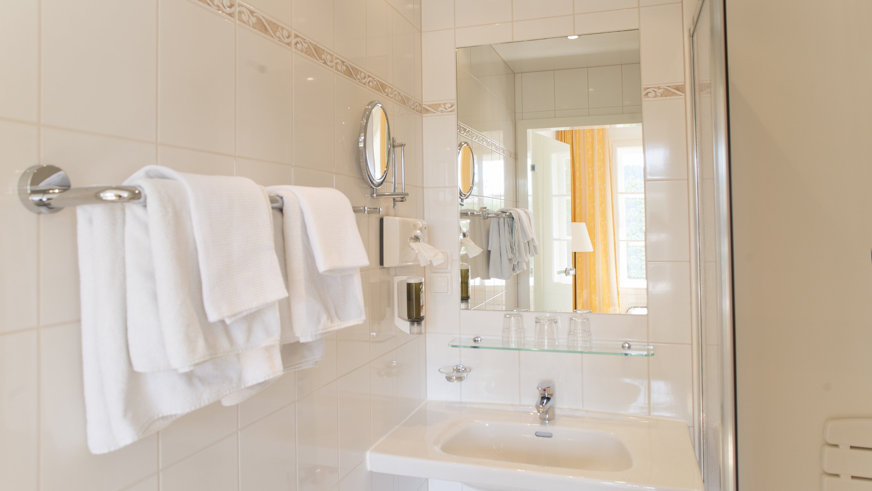 Modernes Badezimmer für jeden Tag Helles Badezimmer mit Waschbecken, Spiegel und ordentlich gefalteten Handtüchern