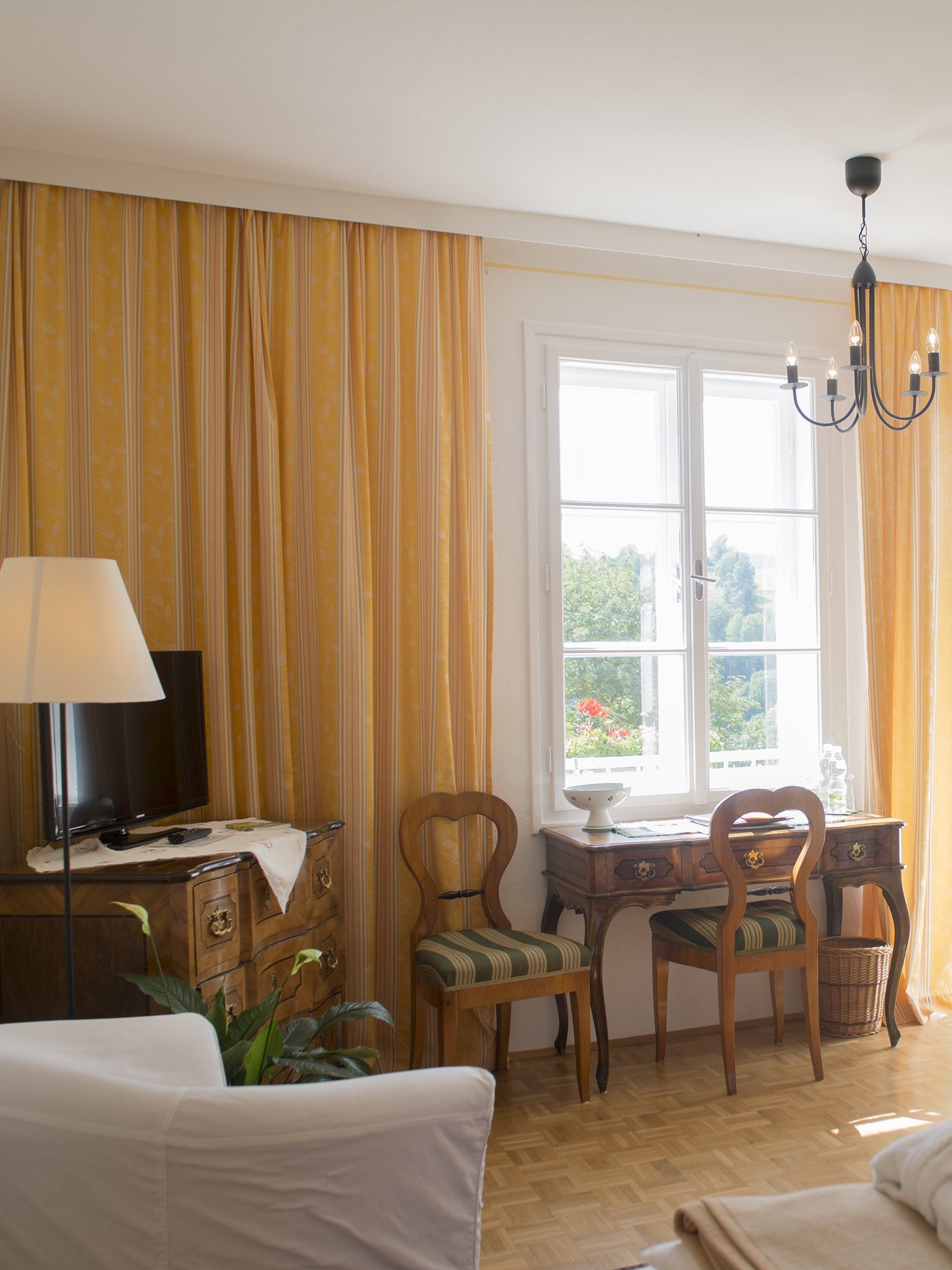 Helles Wohnzimmer mit stilvoller Einrichtung Ein helles Wohnzimmer mit großen Fenstern und einer gemütlichen Einrichtung, einschließlich Tisch und Stühlen.