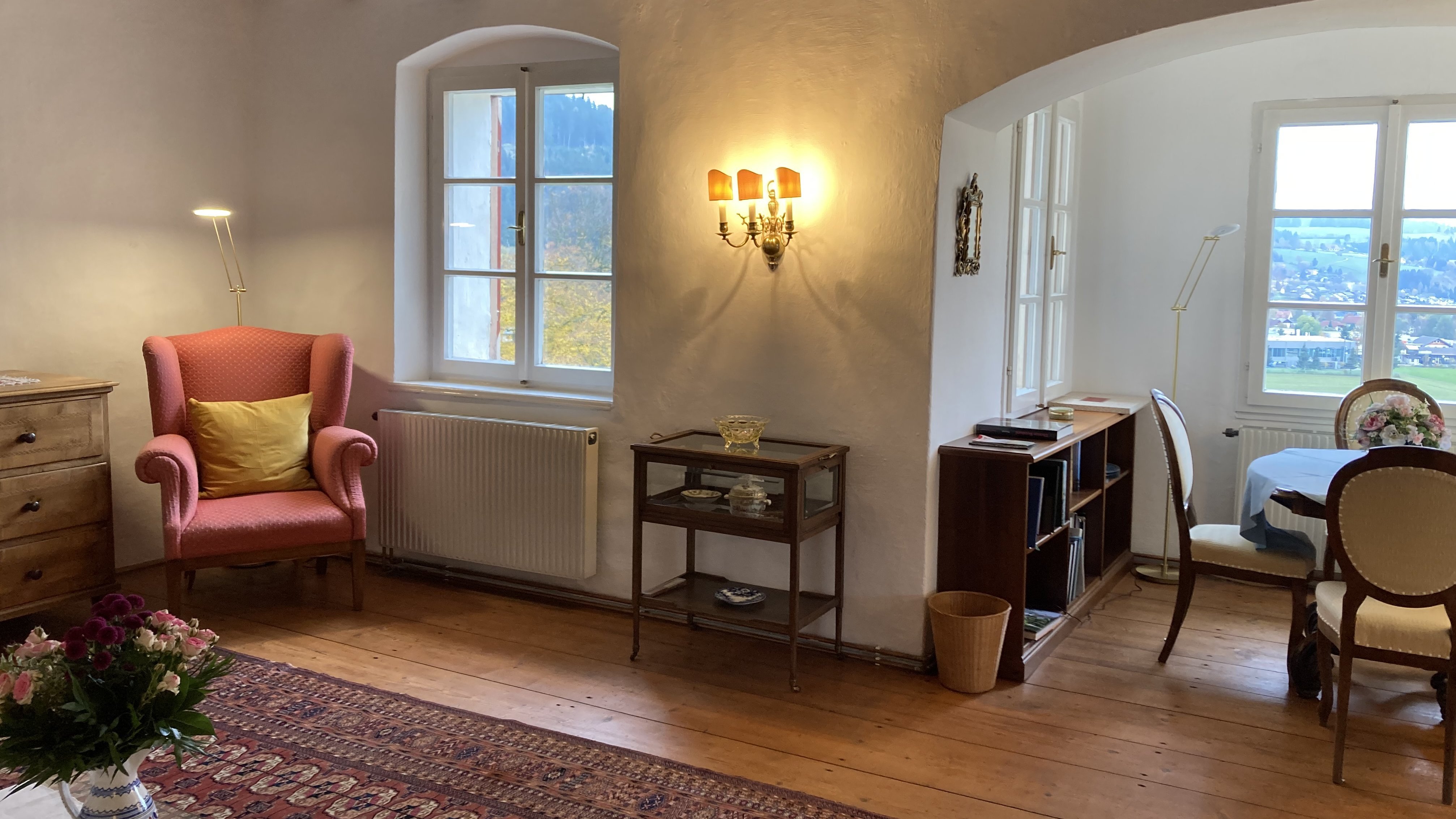 Cozy Living Room with Natural Light A welcoming living room featuring a pink armchair, large windows, and wooden beams.
