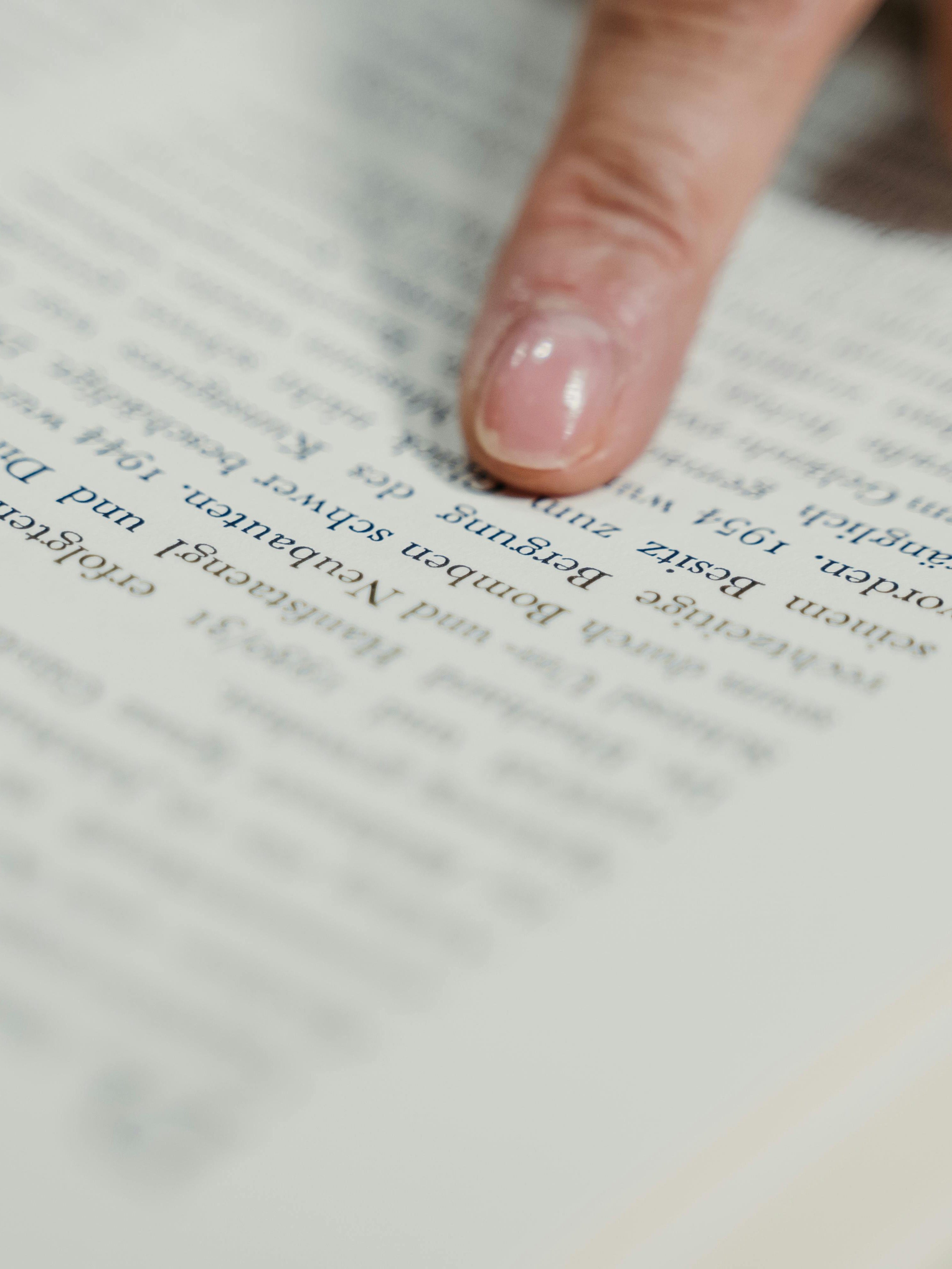 Lesen fördert Wissen Nahaufnahme eines Fingers, der auf den Text in einem offenen Buch zeigt und Bildung symbolisiert.