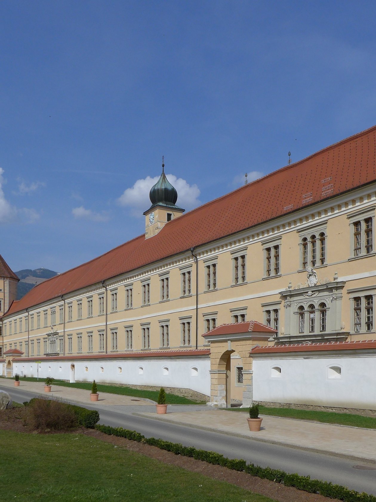 Historische Abtei Seckau in Berglandschaft Großes historisches Klostergebäude vor einer bergigen Kulisse unter blauem Himmel