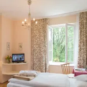 Zimmer mit Doppelbett und Balkontür ist geöffnet.