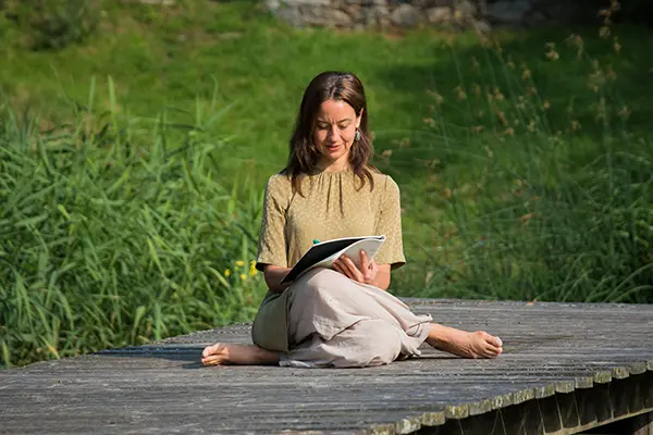 Kurs - Kreative Schreibwerkstatt Frau sitzt am Steg und schreibt.